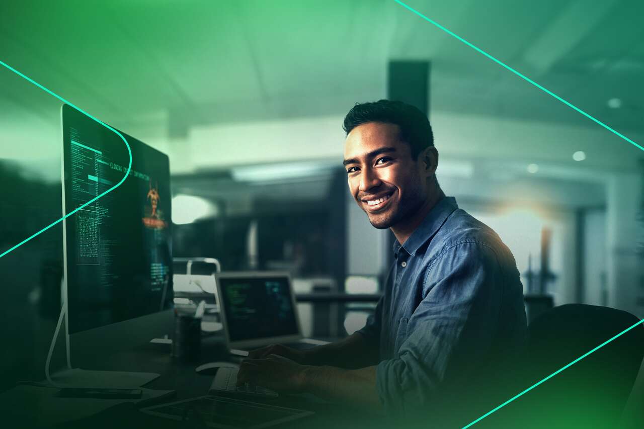 Homem sorrindo enquanto trabalha em computador