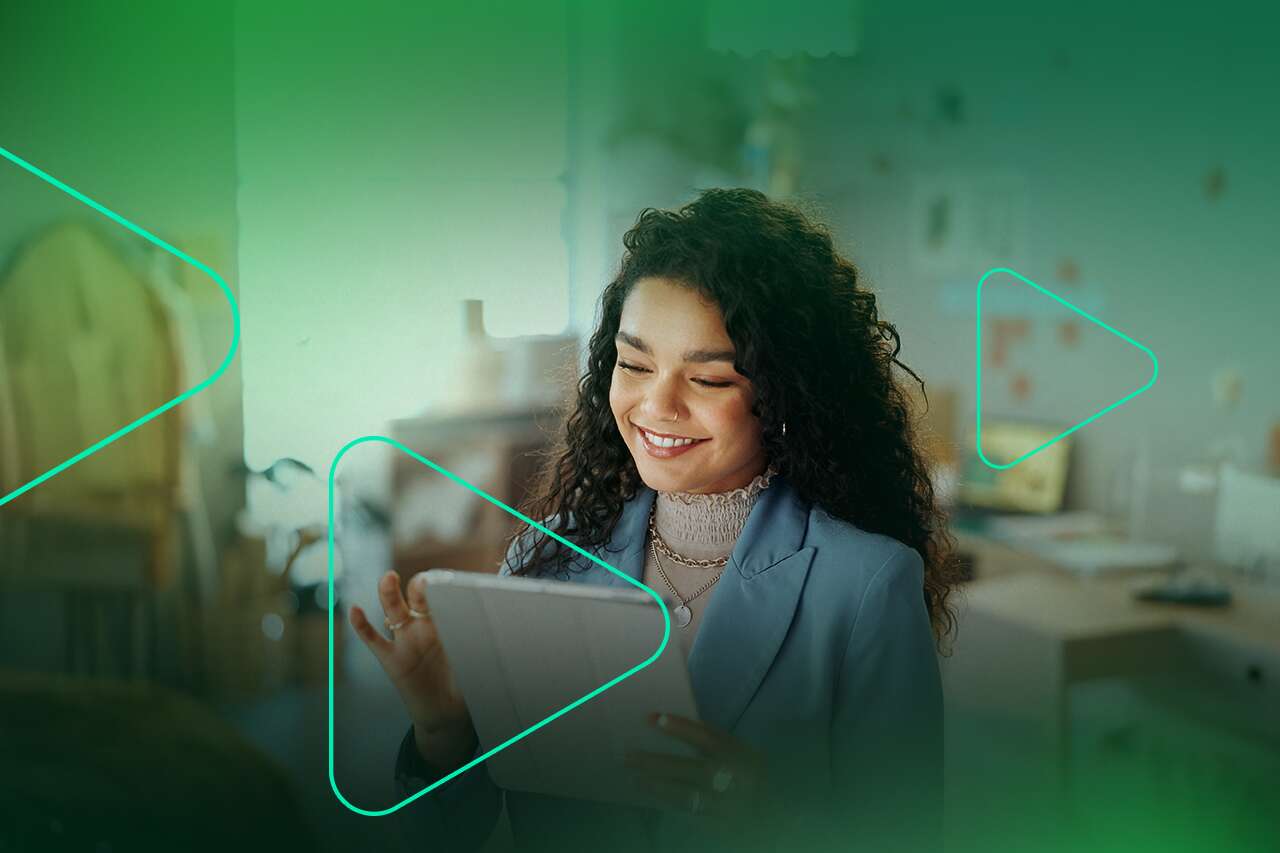 Mulher sorrindo usando tablet em ambiente de trabalho.