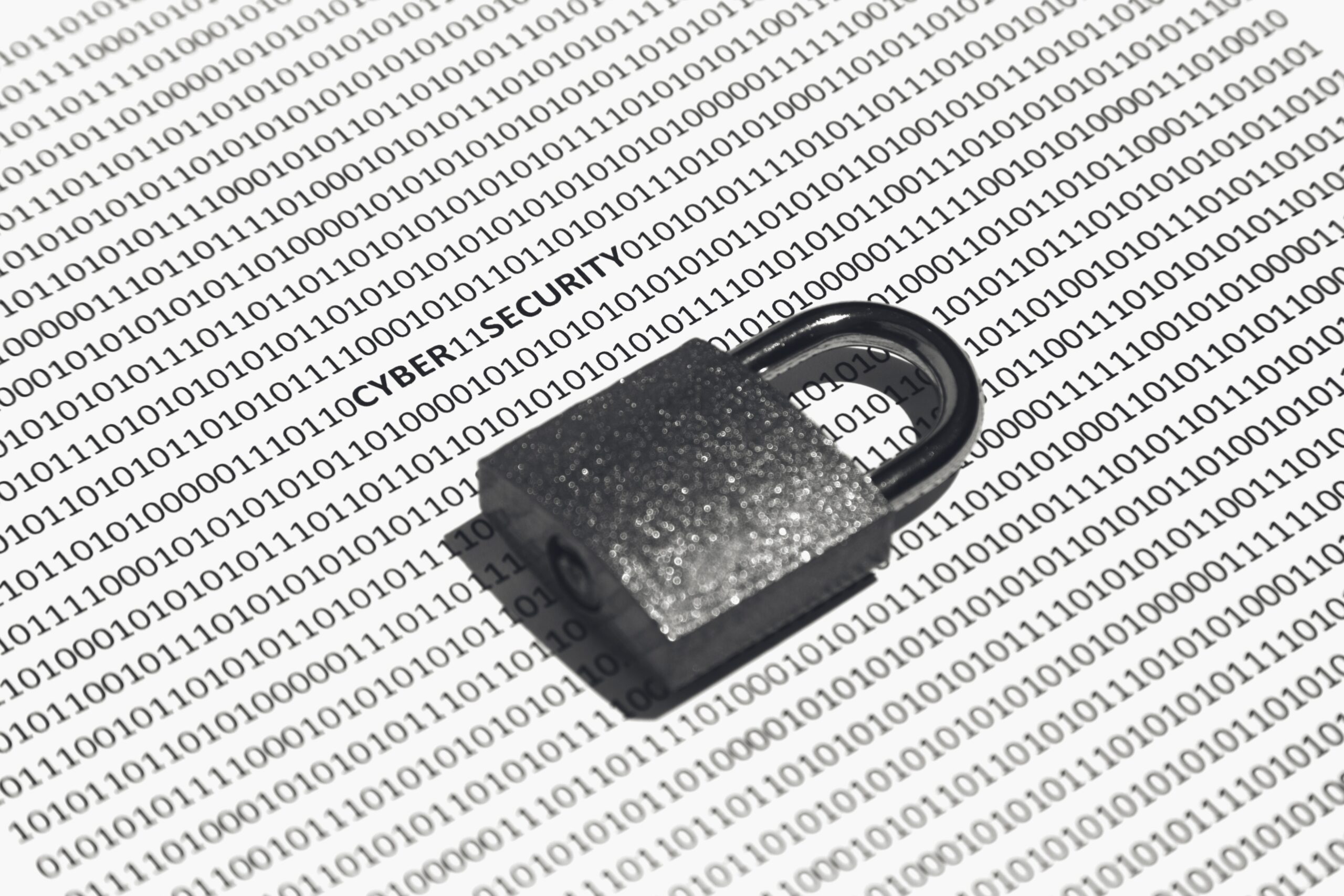 Closeup shot of a lock on a white surface with cyber security, ones, and zeros written on it