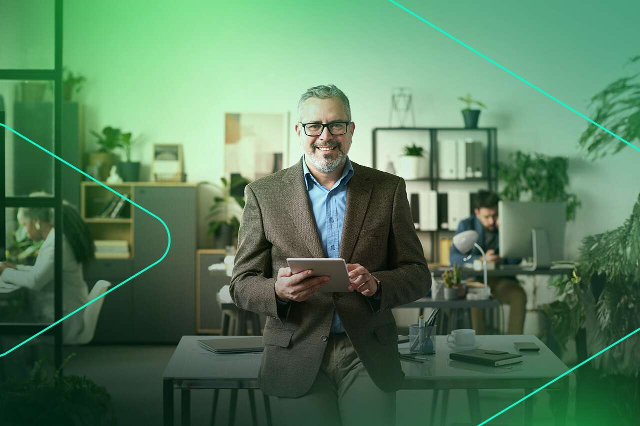 Homem sorrindo em escritório moderno com tablet.
